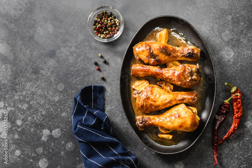 Asian sticky chicken legs in cast iron skillet on dark background. Top view, copy space.