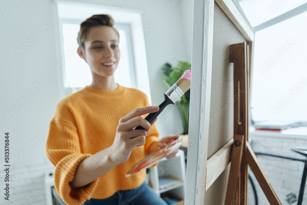 Beautiful young woman looking inspired while drawing in art studio Beautiful young woman looking inspired while drawing in art studio