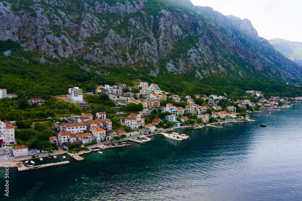 Montenegro. Adriatic Sea. Bay of Kotor. Popular tourist spot. Village on the coast. Houses with orange tiled roofs. Summer. Tourist season. Drone. Aerial view