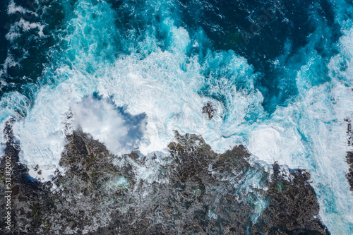 aerial view of ocean waves breaking on rocky coast 