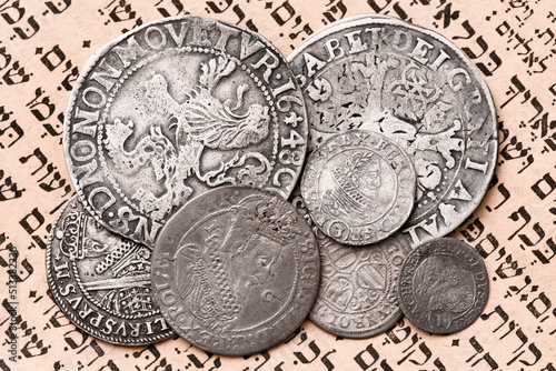 Heap of old silver coins on open Siddur page. Selective focus. Closeup. photo