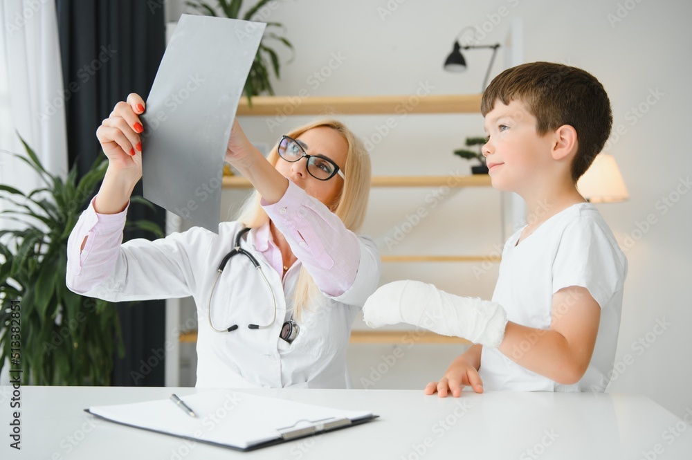 Pediatrician doctor bandaging child's arm. Broken arm in a boy. Pediatrician doctor bandaging child's arm. Broken arm in a boy.