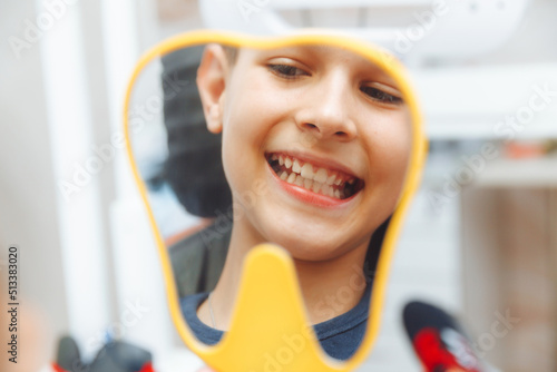 Cuadro en lienzo boy looks in the mirror with a toothy smile, sitting on a chair with a dentist in the dental office