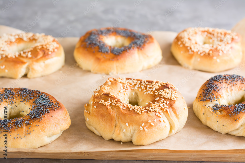 Baked bagels with poppy seeds and sesame seeds on parchment on the table. Homemade pastries
