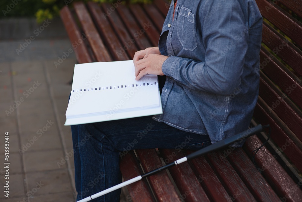 Blind man reading book on bench in park Blind man reading book on bench in park