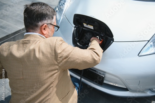 a businessman charges an electric car