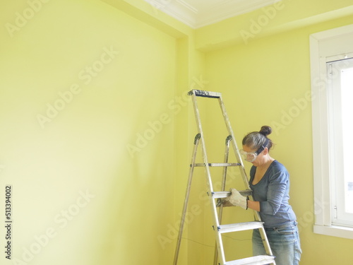 Woman painting a yellow wall