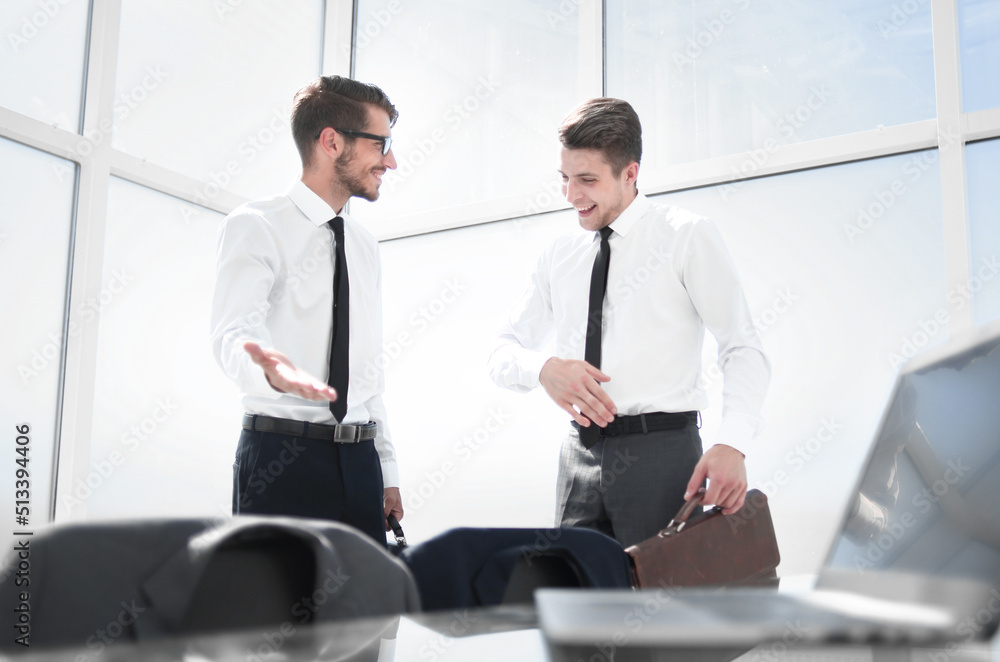 Two businessmen shaking hands standing at big window