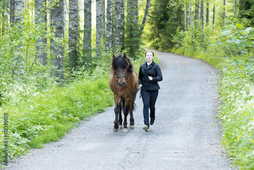 Icelandic horse on gravel road with young woman. Shot in the evening middle of the summer Finland © AnttiJussi