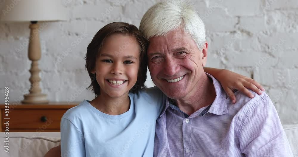 Happy preteen grandkid boy and elder grandfather looking at camera, at each other, away, hugging, smiling, laughing, enjoying family friendship, leisure tome together. Head shot portrait Happy preteen grandkid boy and elder grandfather looking at camera, at each other, away, hugging, smiling, laughing, enjoying family friendship, leisure tome together. Head shot portrait