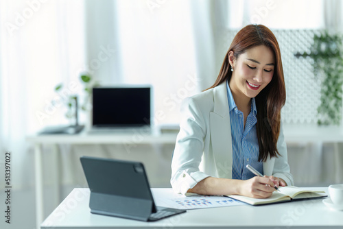 Portrait of a young businesswoman or business owner working with a notebook, tablet computer and documents at office room