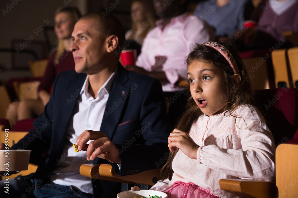 Portrait of surprised preteen girl sitting with her mouth open in cinema and watching interesting adventure movie