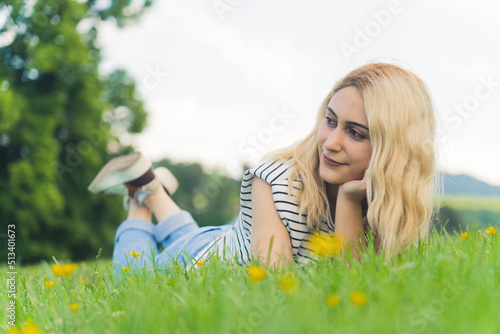 blonde European girl lying on the grass and looking beside. outdoor full shot. High quality photo