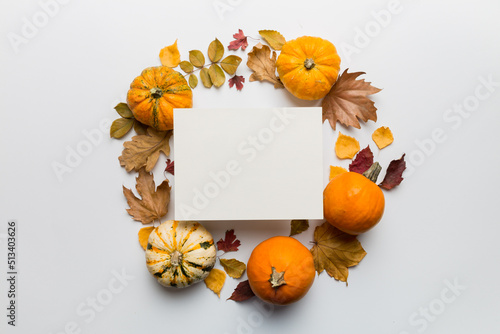 Autumn composition with paper blank and dried leaves with pumpkin on table. Flat lay, top view, copy space