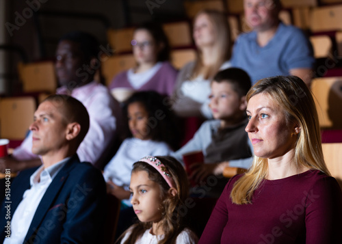 Young woman spending time with her family, watching together interesting movie in picture theater