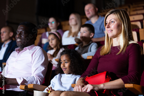 international parents with children sitting at movie in cinema