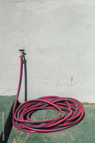 Obraz na płótnie Faucet with coiled hose on the green floor of the port w salonie
