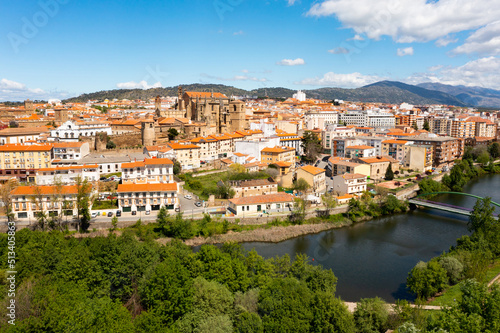 Picturesque aerial view of Plasencia city located in valley of Jerte river overlooking terracotta tiled roofs of residential buildings and medieval cathedral complex in spring, Extremadura, Spain