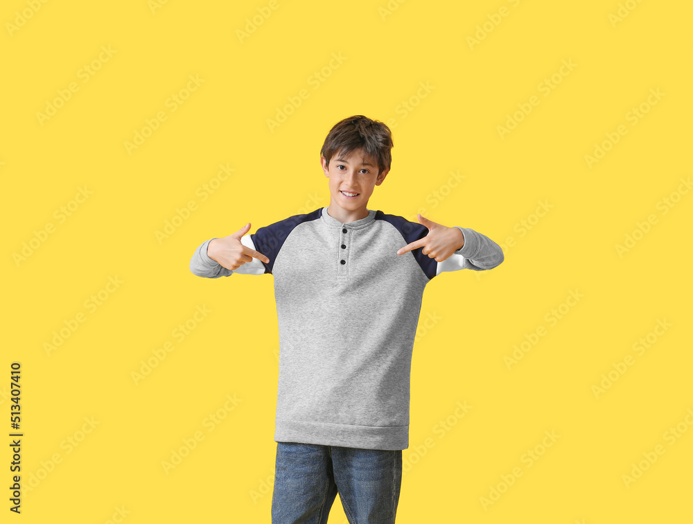 Teenage boy pointing at shirt on yellow background Teenage boy pointing at shirt on yellow background