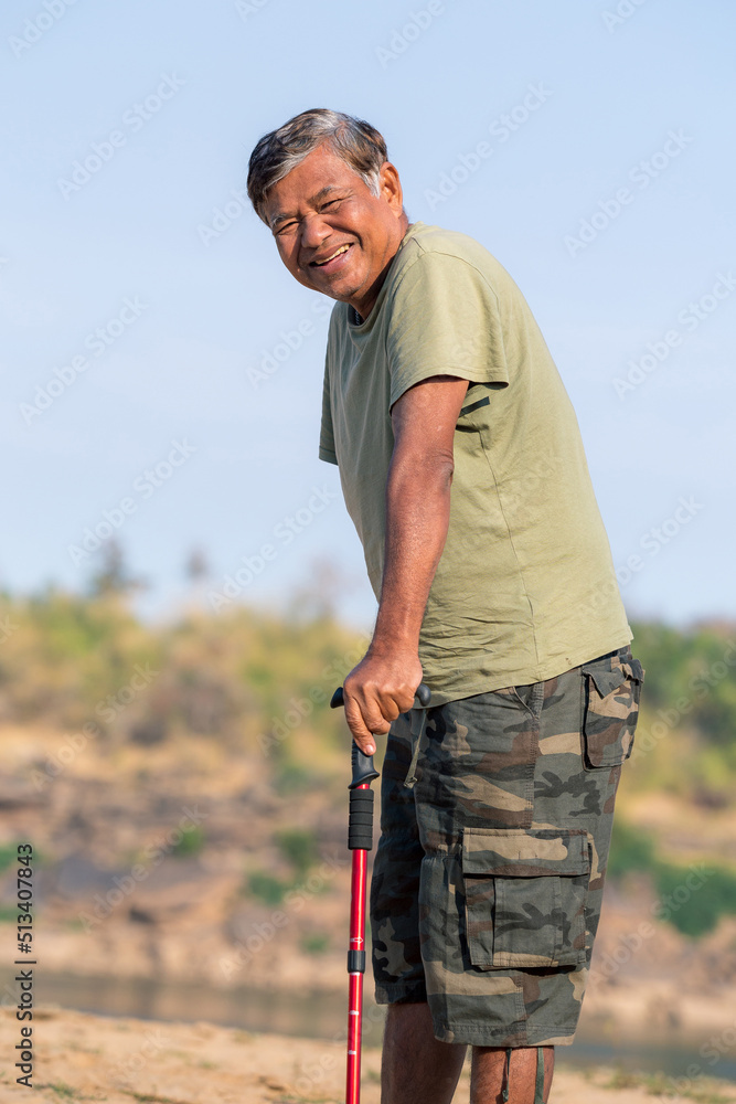 elderly man with a cane smiling and posing in a park, outdoor