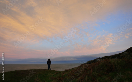 Silhouette of a man against the background of the sky illuminated by the setting sun.