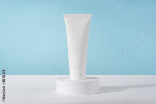 Cosmetic luxury cream tube bottle mockup on blue background on pedestal podium. Unbranded lotion beauty product packaging. Product presentation mock up. Lotion, mousse, cleanser for skincare routine photo