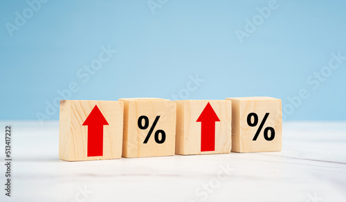 Finance and interest rate concept. Wooden cubes with arrows up and percentage symbol over a blue background