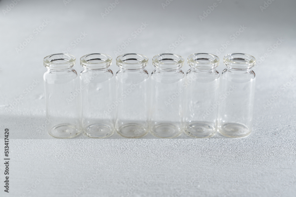 hilera de 6 botellas pequeñas de vidrio sobre fondo con textura claro, llenos de agua, simple y limpio. hilera de 6 botellas pequeñas de vidrio sobre fondo con textura claro, llenos de agua, simple y limpio.