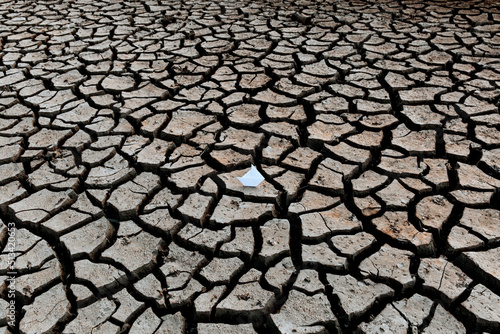 White paper boat on dry, dry soil with cracks. Global warming concept