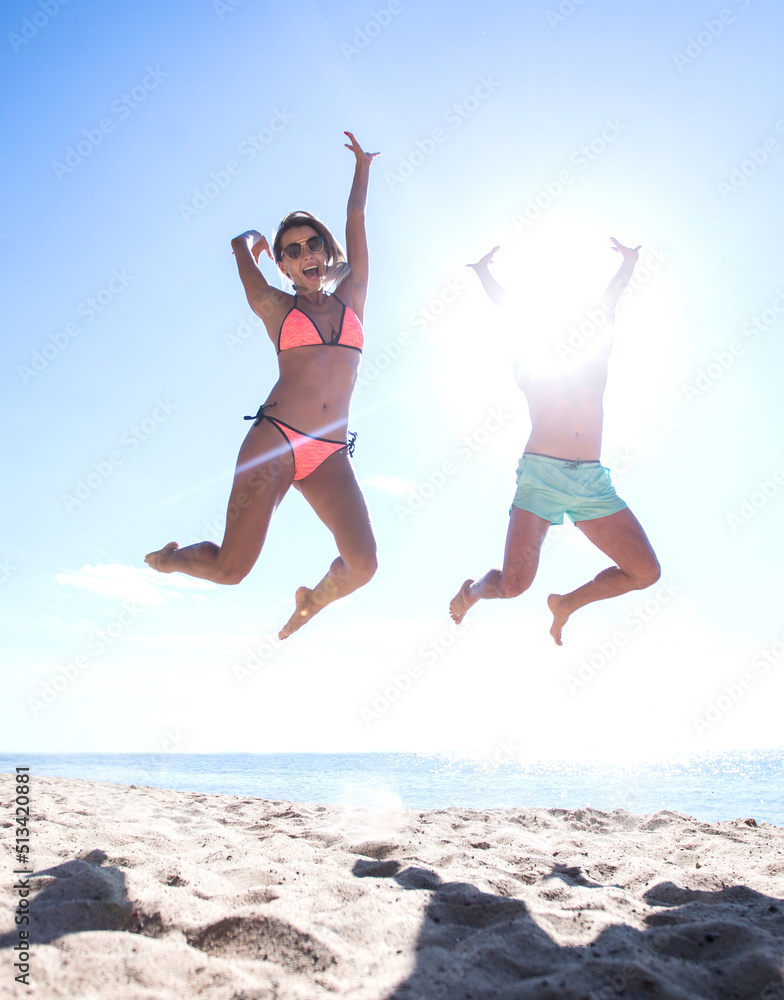 Happy couple jumping on beach.