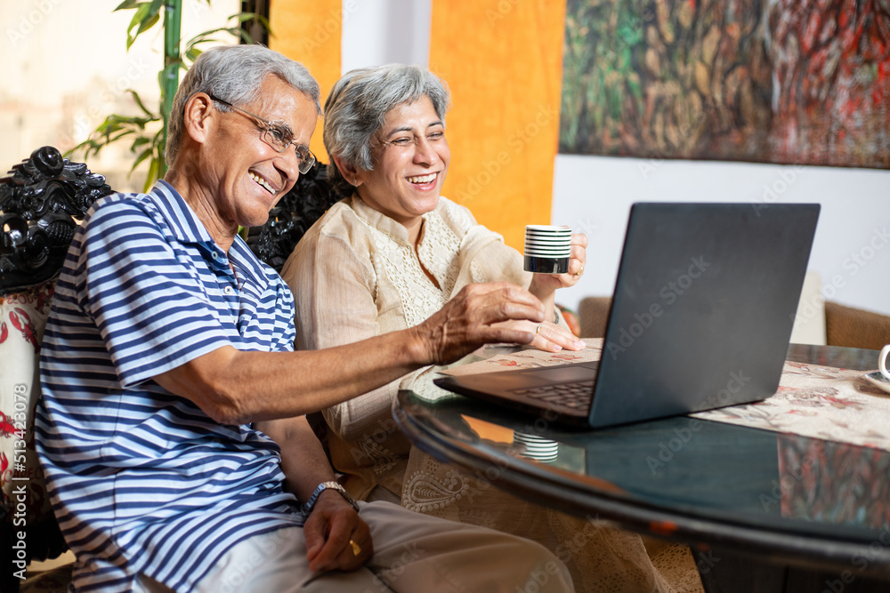 Happy indian senior couple using laptop, Retired old husband and wife spend time together at home. use of technology.