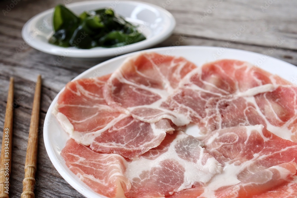 Wakame seaweed and raw pork shabu on wood background