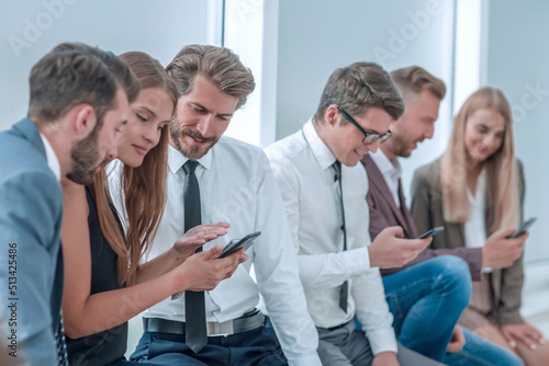 young employees of the company looking at the screens of their smartphones