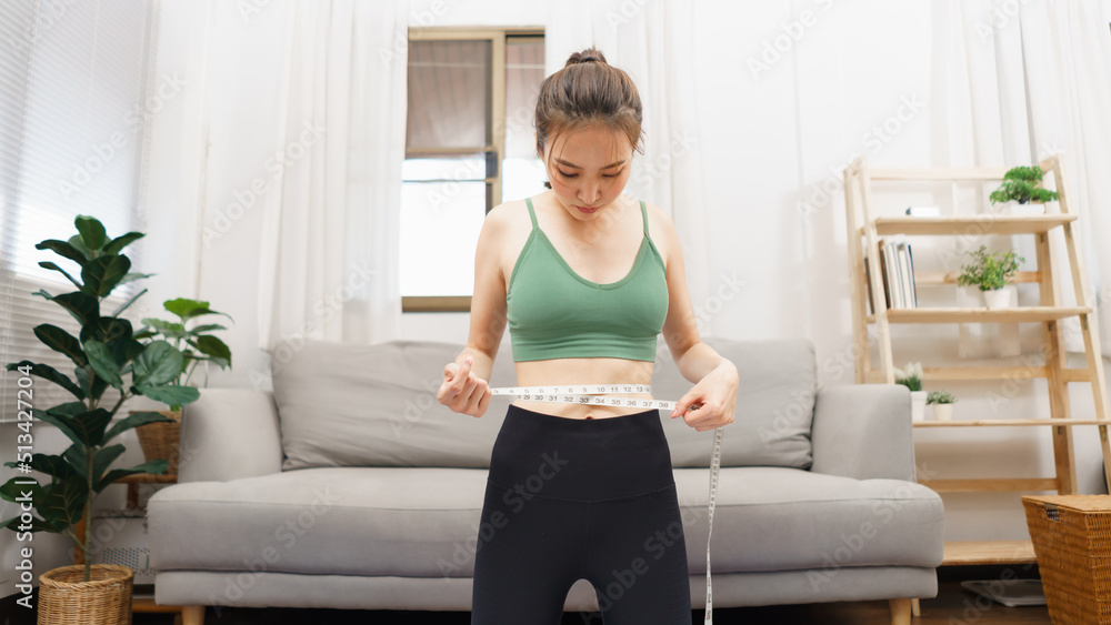 Healthy and weight loss concept, Young Asian woman use tape measure to measuring her waist size Healthy and weight loss concept, Young Asian woman use tape measure to measuring her waist size