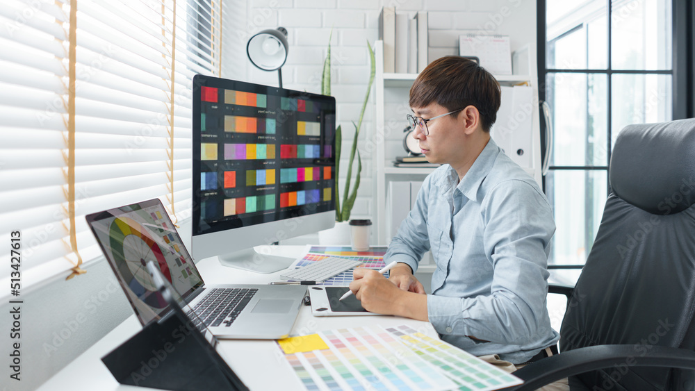 Creativity concept, Male graphic designer using tablet and looking color swatch samples on screen