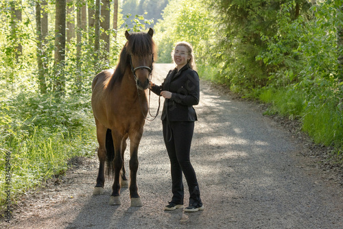 Icelandic horse on gravel road with young woman. Shot in the evening middle of the summer in Finland © AnttiJussi