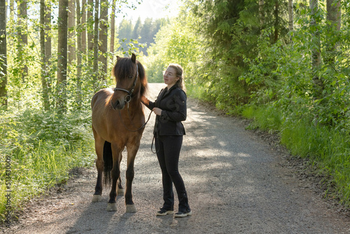 Icelandic horse on gravel road with young woman. Shot in the evening middle of the summer in Finland