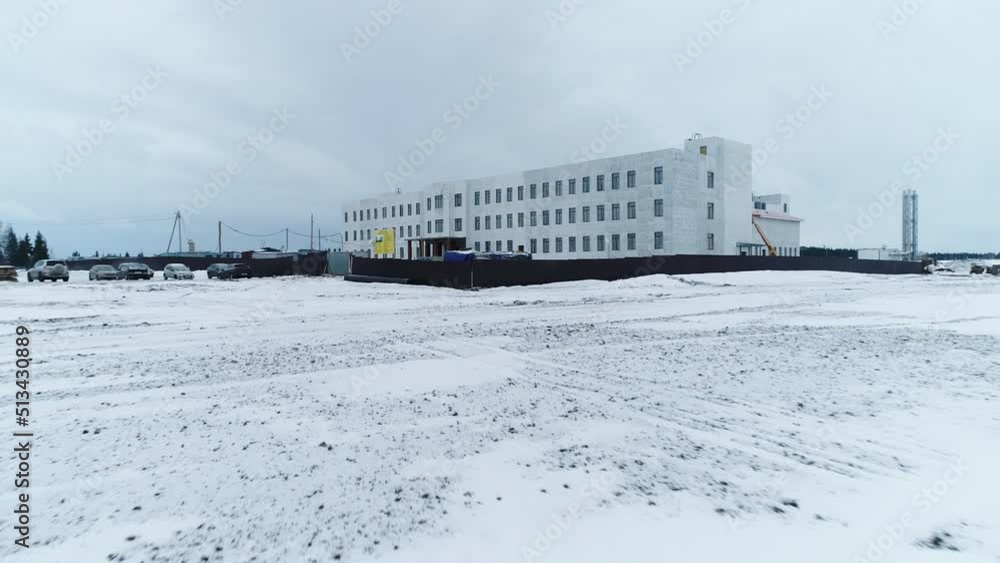 Construction site of industrial building in snowy field on gloomy winter day. Future plant office building at rural site Construction site of industrial building in snowy field on gloomy winter day. Future plant office building at rural site