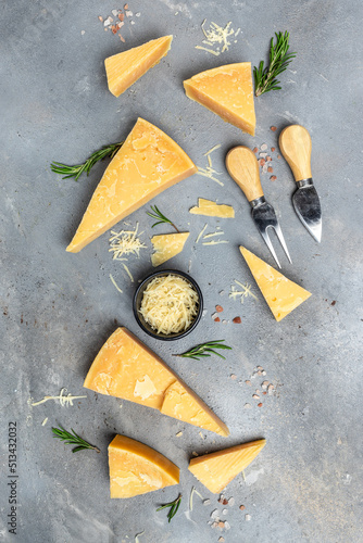 Parmesan cheese on a wooden board, Hard cheese, rosemary and cheese knife on a gray background. vertical image. top view