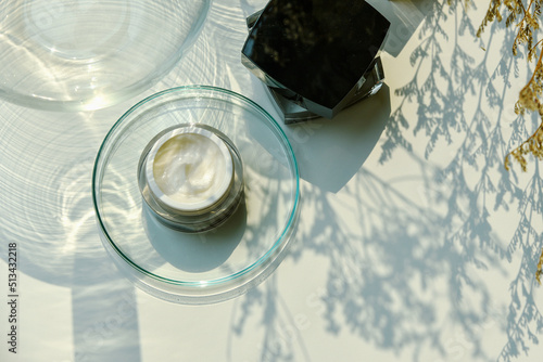 Cosmetic bottle container on sunlight and leaves plant shadow background, Skincare facial cream, Beauty product with warm mood and tone.