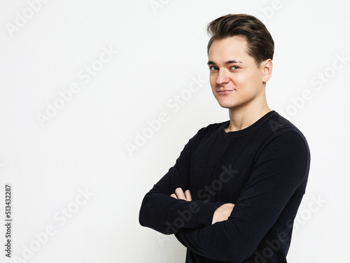 Young handsome man wearing black sweater crossing hands and look at camera