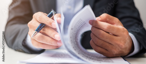 Businessman signing on contract documents after reading, man holding pen and approve on business report. Contract agreement, partnership and deal concepts photo