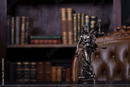 Judge office. Themis sculpture and gavel on the judge desk. Book shelf and judge chair in the background.