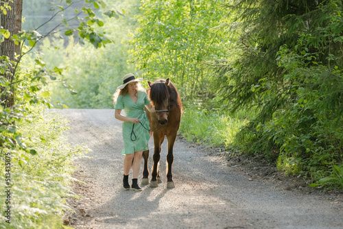 Icelandic horse on gravel road with young woman. Shot in the evening middle of the summersummer in Finland