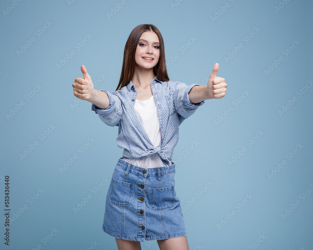 High fashion photo of a beautiful elegant young happy woman in a pretty denim skirt, shirt, stylish sunglasses white top posing on blue background. Slim figure, studio shot. High fashion photo of a beautiful elegant young happy woman in a pretty denim skirt, shirt, stylish sunglasses white top posing on blue background. Slim figure, studio shot.