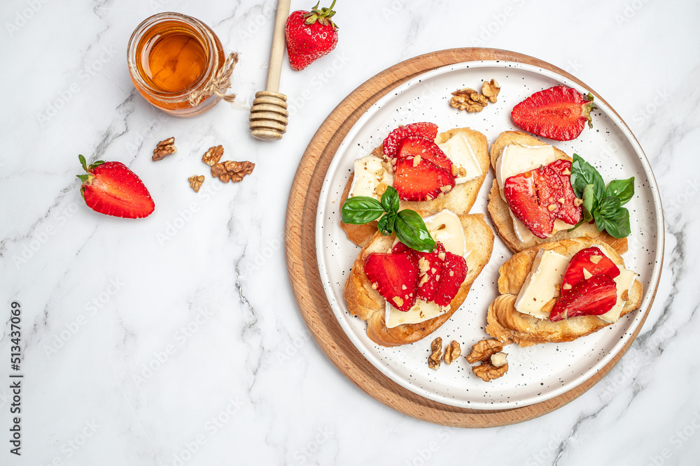 Two toasts or bruschetta with trawberries, cheese camembert nuts and honey. Summer breakfast. Healthy, clean eating. Vegan or gluten free diet