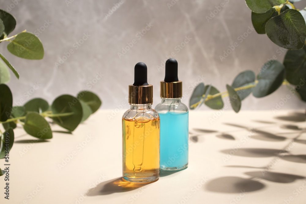 Cosmetic bottles serum or oil with branch eucalyptus on grey marble background. Natural cosmetics concept, skin care product. Beauty concept for face body care Cosmetic bottles serum or oil with branch eucalyptus on grey marble background. Natural cosmetics concept, skin care product. Beauty concept for face body care