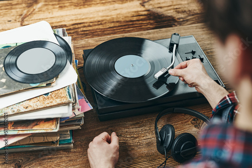 Man listening to music from vinyl record. Playing music from analog disk on turntable player. Enjoying music from old collection. Retro and vintage photo