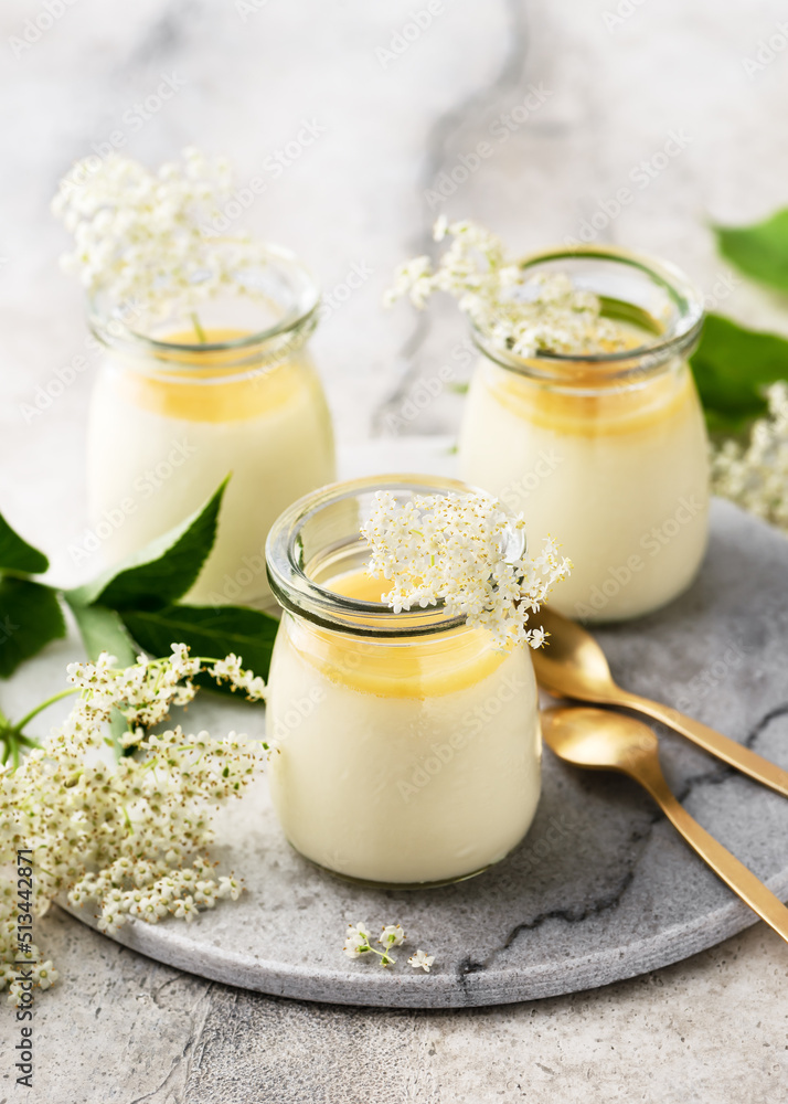 Delicious Italian elder flower dessert, panna cotta with lemon sauce and fresh flowers in portion glass jars. Homemade organic food concept. Delicious Italian elder flower dessert, panna cotta with lemon sauce and fresh flowers in portion glass jars. Homemade organic food concept.