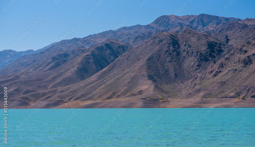The coastline of one of the many lakes in Tibet is surrounded by rocky mountains. Unusual, unexplored nature of Tibet. Remote beautiful places.